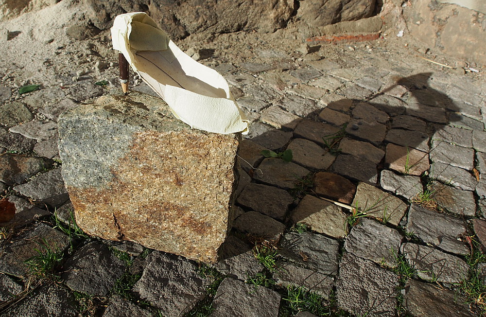 Pflasterstein mit Damenschuh, der einen Bleistift als Stöckelabsatz hat